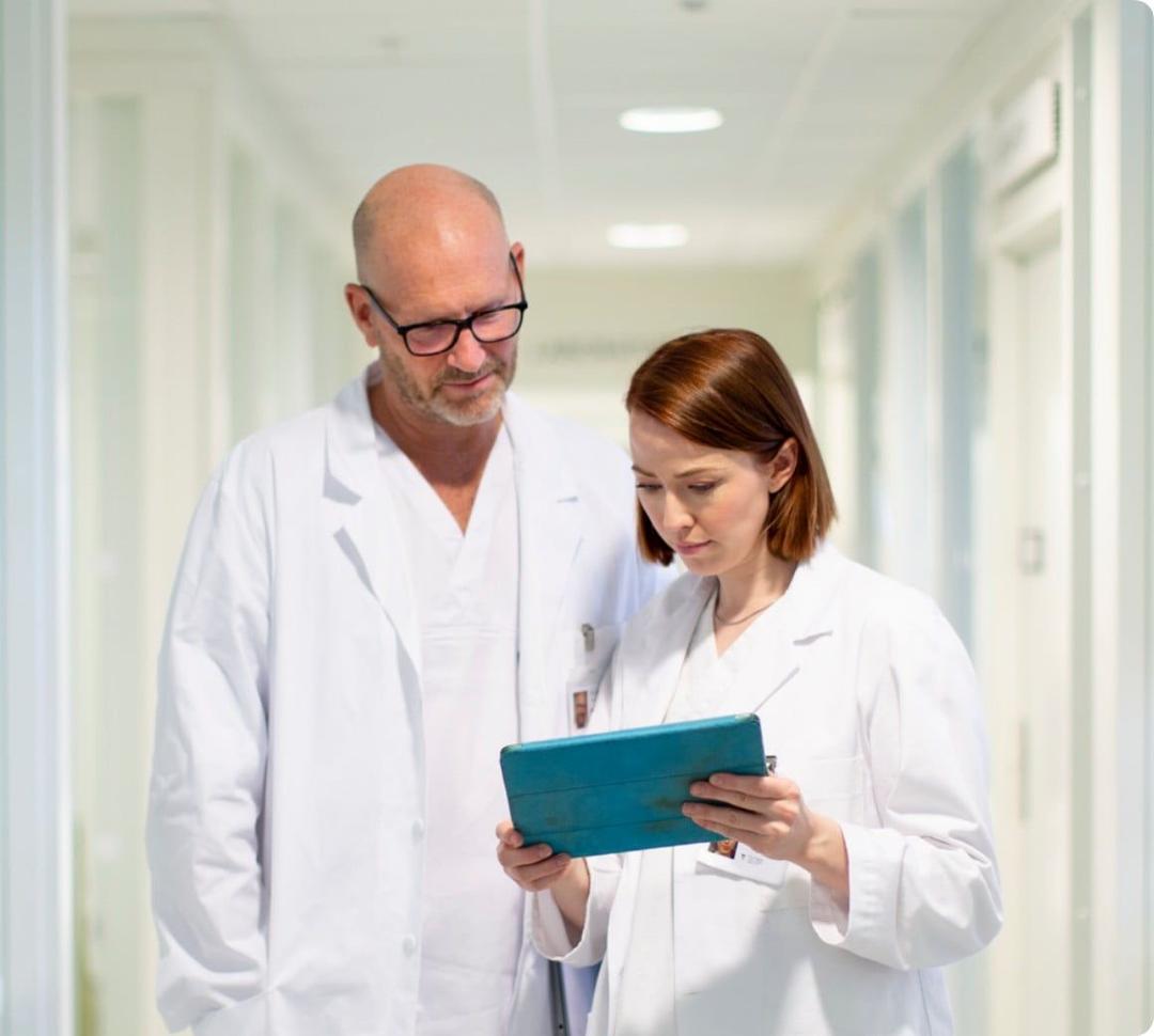 Healthcare professionals viewing tablet in corridor